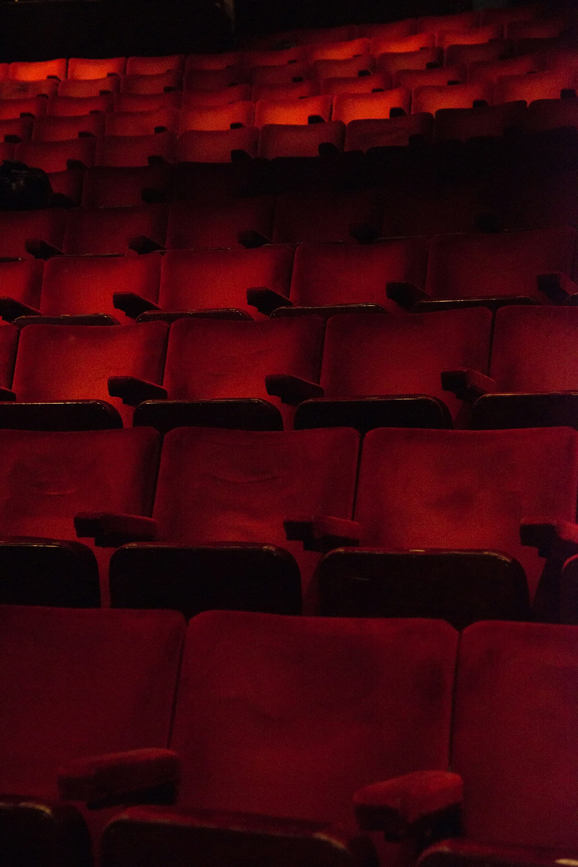 Rows of empty red cinema seats. Temporary Unsplash artwork.