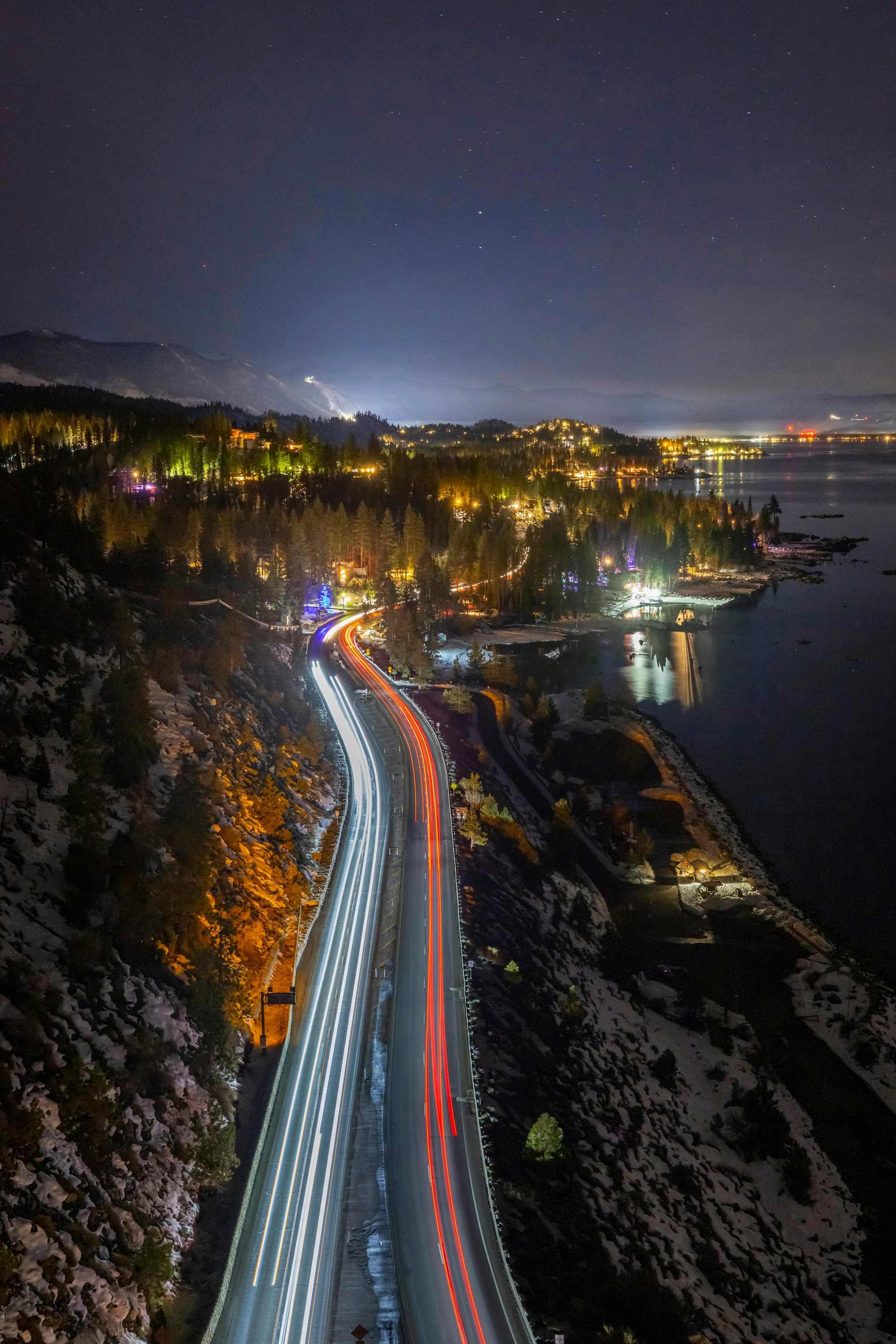 A winding road beside a lake at night. Temporary Unsplash artwork.
